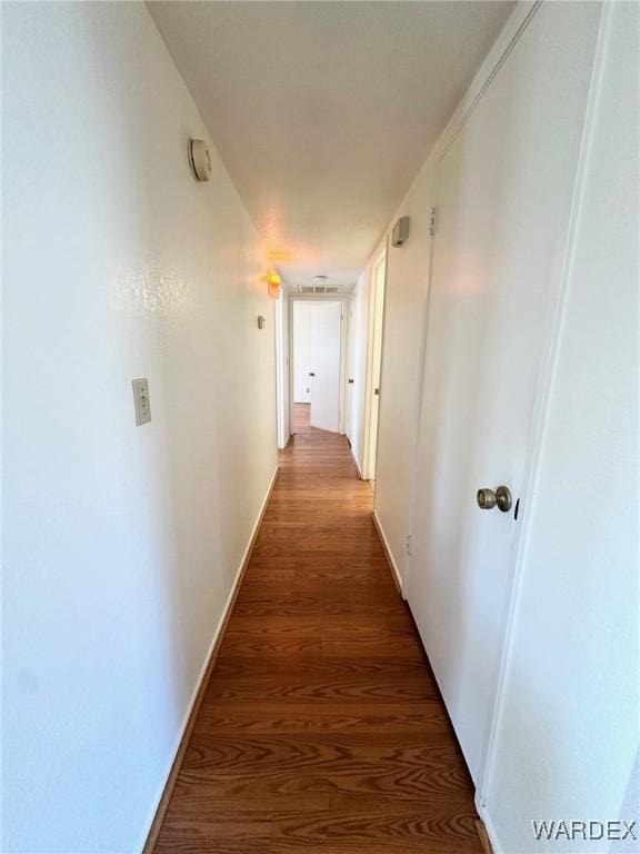 corridor featuring baseboards and wood finished floors