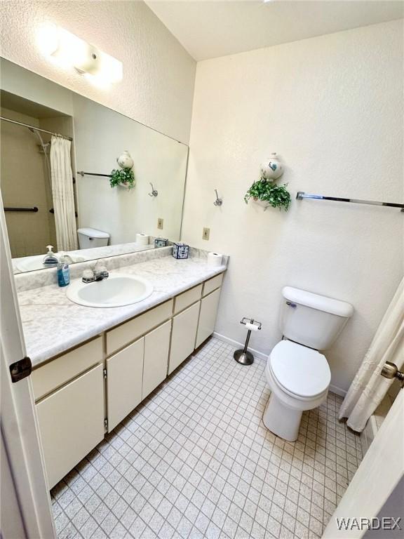 bathroom featuring a shower with curtain, baseboards, vanity, and toilet