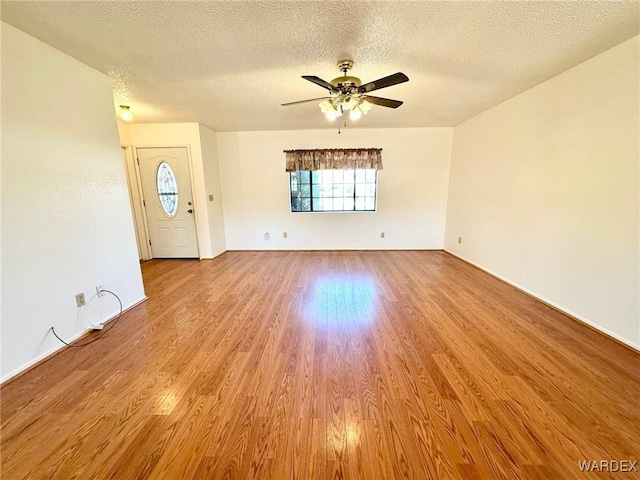 unfurnished living room featuring a textured ceiling, wood finished floors, and a ceiling fan