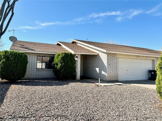 ranch-style house with an attached garage, a shingled roof, concrete driveway, and brick siding