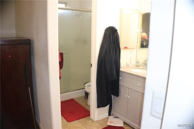 full bath with a stall shower, vanity, toilet, and tile patterned floors