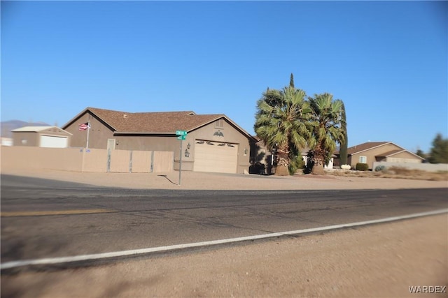 view of front of home with a garage, concrete driveway, fence, and stucco siding