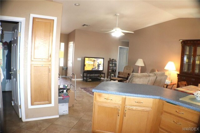 kitchen featuring dark countertops, vaulted ceiling, light brown cabinets, and open floor plan