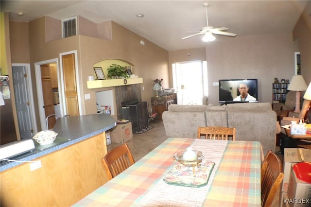 dining room featuring a fireplace, visible vents, vaulted ceiling, and a ceiling fan