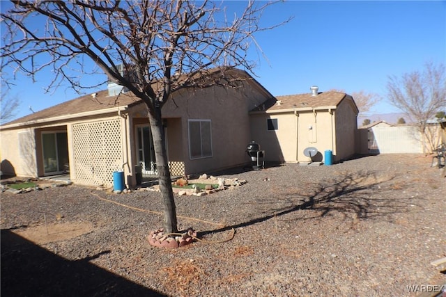 back of house featuring fence and stucco siding