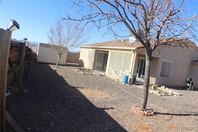 rear view of property featuring an outbuilding, a shed, and stucco siding