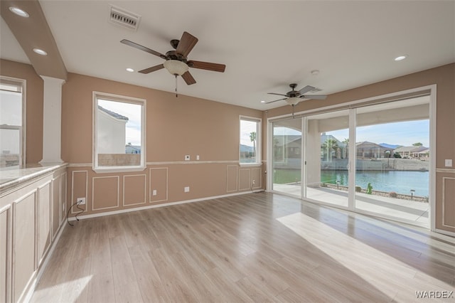 spare room with recessed lighting, a decorative wall, a water view, visible vents, and light wood-style floors