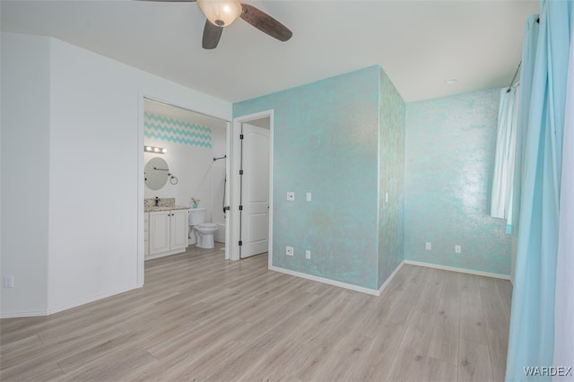 unfurnished bedroom featuring a ceiling fan, light wood-type flooring, connected bathroom, and baseboards