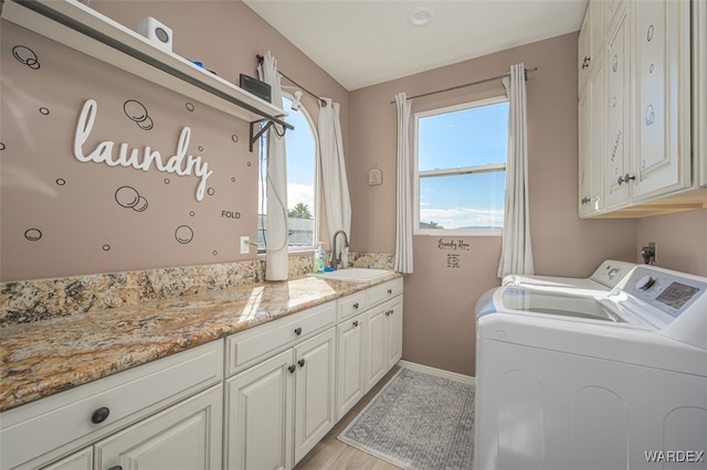 washroom featuring baseboards, a sink, cabinet space, and washer and dryer