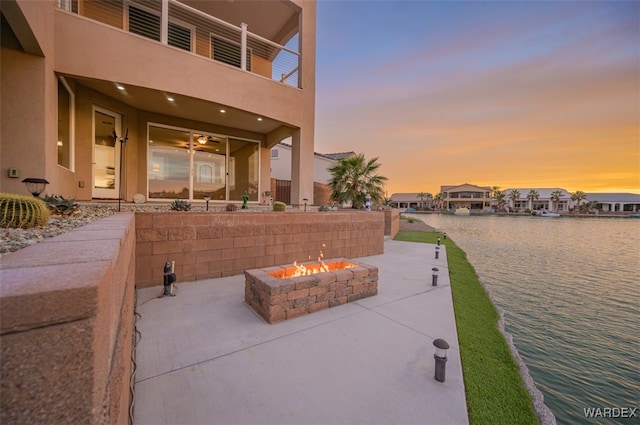 view of patio featuring a water view, a balcony, and an outdoor fire pit