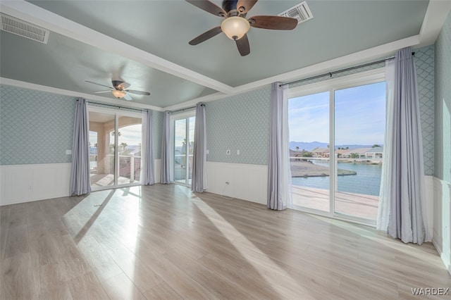 unfurnished room featuring wallpapered walls, visible vents, a water and mountain view, and a wainscoted wall