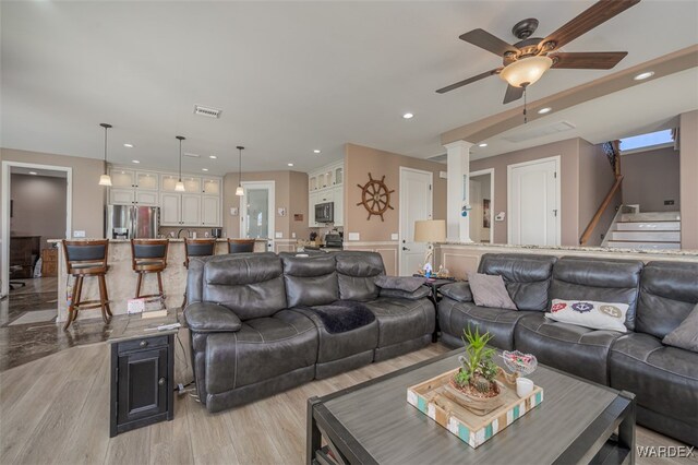 living area featuring decorative columns, recessed lighting, visible vents, stairway, and light wood-type flooring