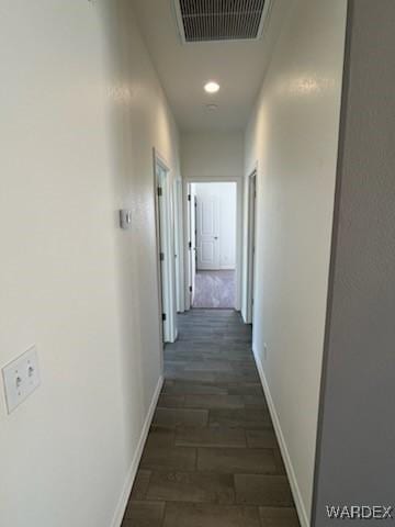 corridor with baseboards, visible vents, and dark wood finished floors