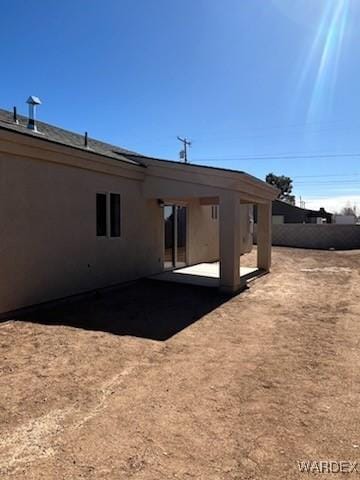 rear view of property featuring a patio area, fence, and stucco siding