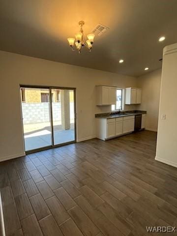 kitchen with plenty of natural light, dark countertops, an inviting chandelier, and white cabinets