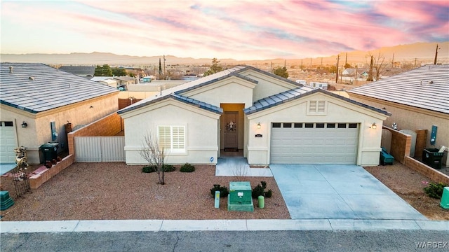 ranch-style house featuring a mountain view, a garage, fence, driveway, and stucco siding