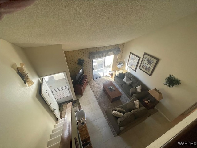 living area featuring wallpapered walls, a textured ceiling, baseboards, and tile patterned floors