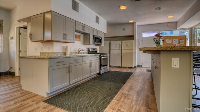 kitchen with appliances with stainless steel finishes, a breakfast bar, visible vents, and gray cabinetry