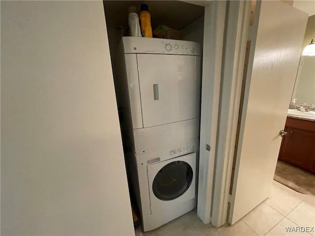 clothes washing area featuring laundry area, light tile patterned floors, a sink, and stacked washer and clothes dryer