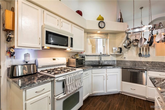 kitchen with white appliances, a sink, dark wood-style floors, white cabinets, and dark stone counters