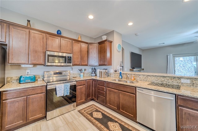 kitchen with light stone counters, recessed lighting, a sink, appliances with stainless steel finishes, and brown cabinetry