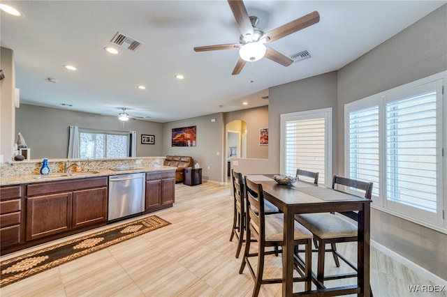 kitchen with arched walkways, a sink, visible vents, light stone countertops, and dishwasher