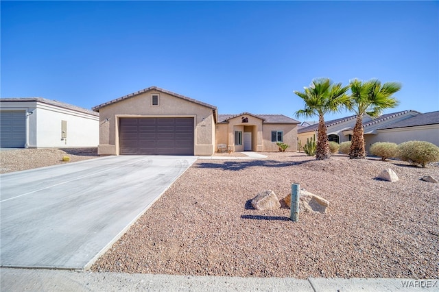 mediterranean / spanish-style house with an attached garage, a tiled roof, concrete driveway, and stucco siding