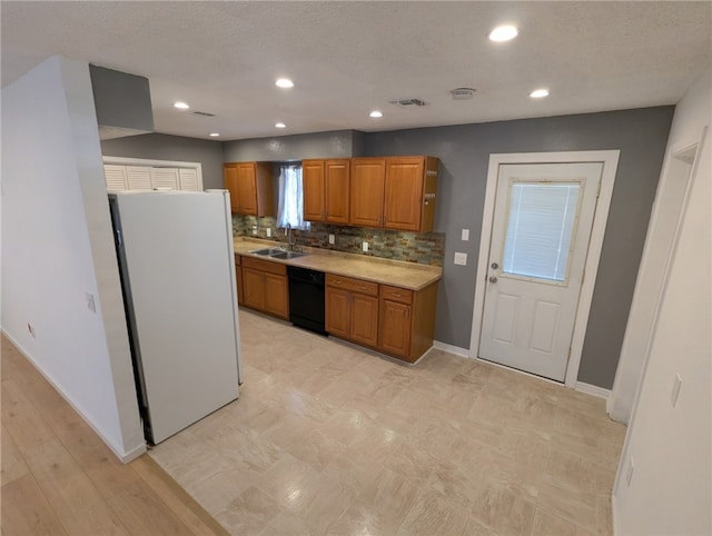 3166 E Thompson Ave, Kingman, AZ 86409 - kitchen with freestanding refrigerator, black dishwasher, brown cabinetry, light countertops, and baseboards
