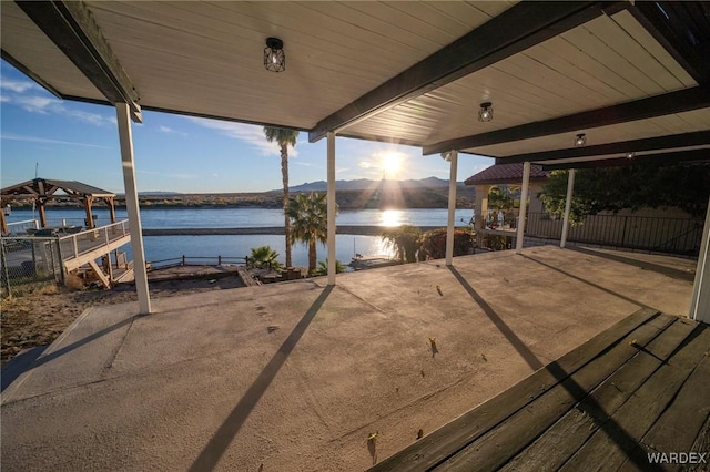 view of patio / terrace featuring a water view and fence