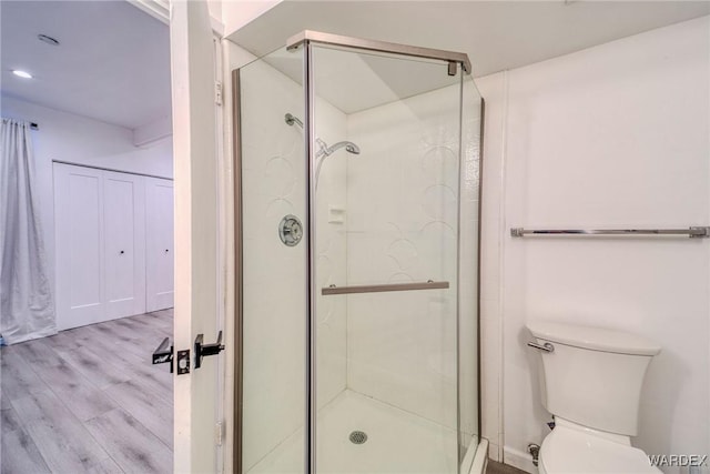 full bath featuring wood finished floors, toilet, and a shower stall