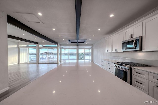 kitchen featuring white cabinets, beamed ceiling, stainless steel appliances, light countertops, and recessed lighting