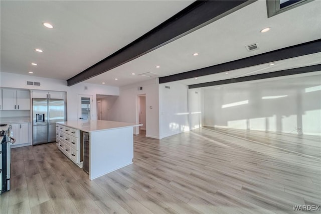 kitchen featuring light countertops, white cabinets, stainless steel built in fridge, and open floor plan