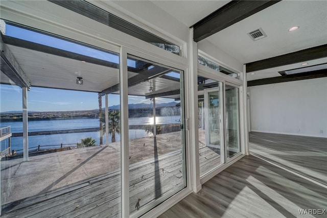 unfurnished sunroom featuring a water view, visible vents, and beamed ceiling