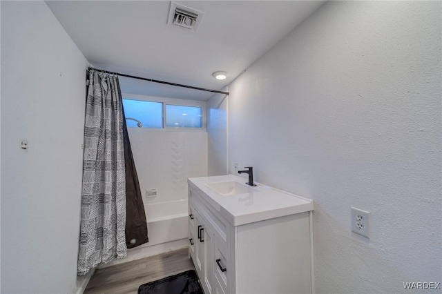 full bathroom featuring visible vents, shower / bathtub combination with curtain, vanity, and wood finished floors