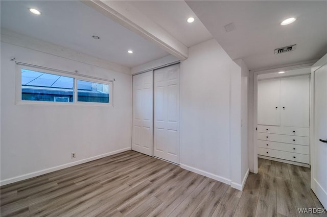 unfurnished bedroom with light wood-style floors, baseboards, and visible vents