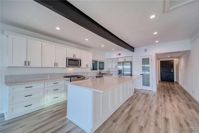 kitchen featuring a center island, stainless steel appliances, light countertops, white cabinets, and a sink