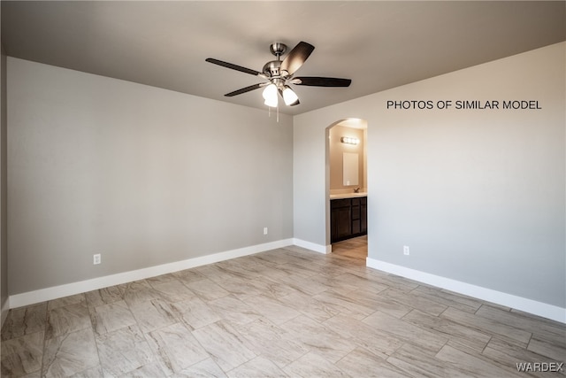 empty room with a ceiling fan, arched walkways, and baseboards