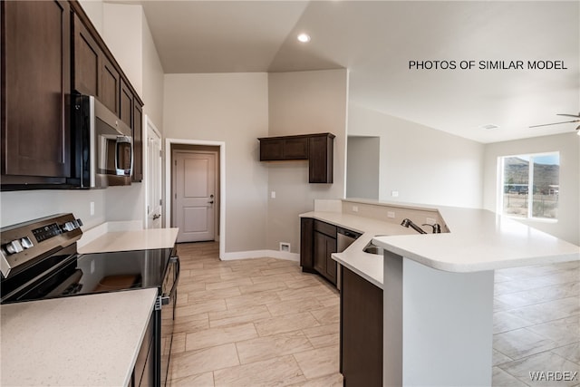 kitchen with stainless steel appliances, dark brown cabinets, a sink, and light countertops