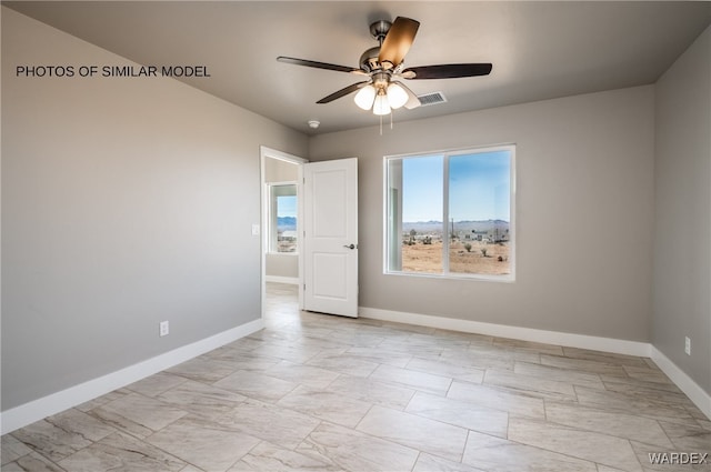 empty room with a ceiling fan and baseboards