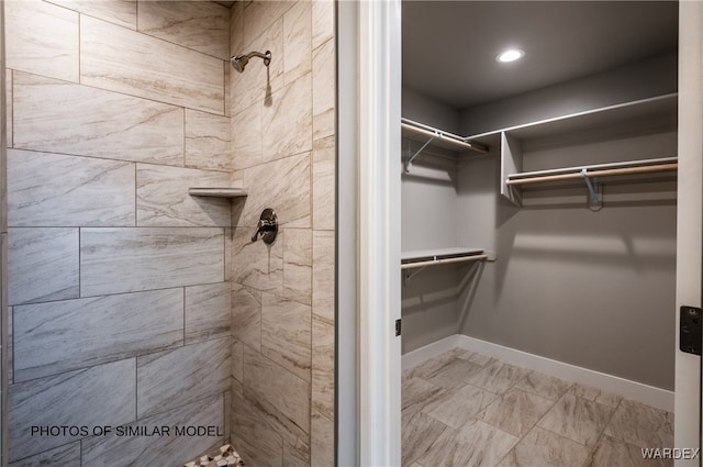 bathroom featuring a stall shower, a walk in closet, and baseboards