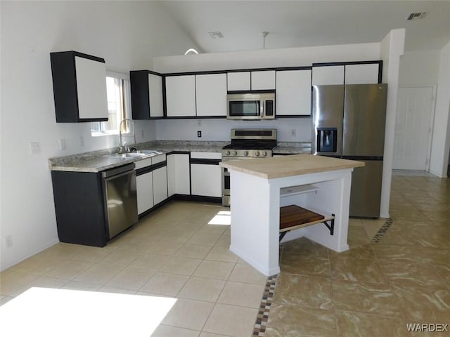 kitchen with appliances with stainless steel finishes, light countertops, a sink, and white cabinetry