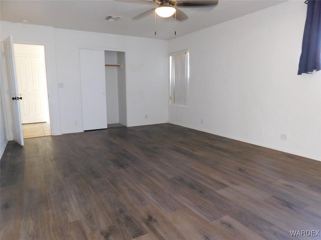 unfurnished bedroom with a closet, dark wood-style flooring, visible vents, and ceiling fan