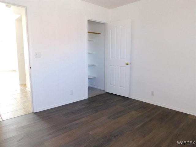 unfurnished bedroom featuring a closet, baseboards, and wood finished floors