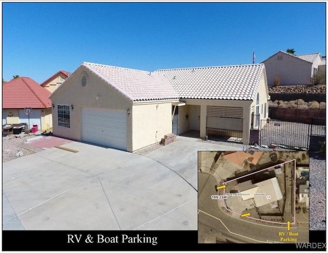 ranch-style home featuring a tile roof, stucco siding, concrete driveway, an attached garage, and fence