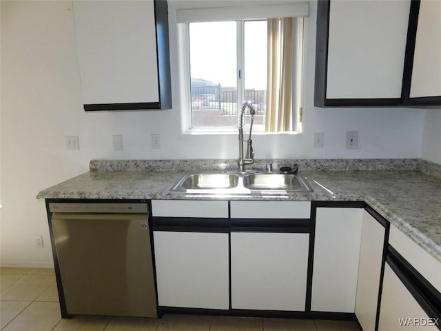 kitchen with white cabinets, light countertops, stainless steel dishwasher, a sink, and light tile patterned flooring