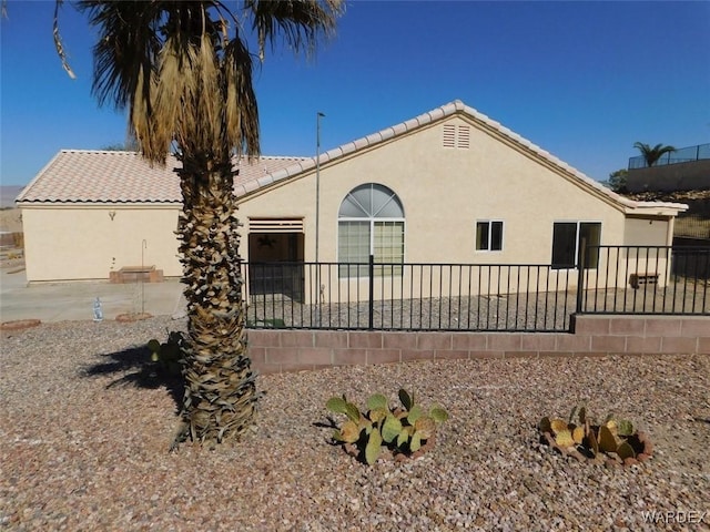 view of front of house featuring a patio area, a tile roof, and stucco siding