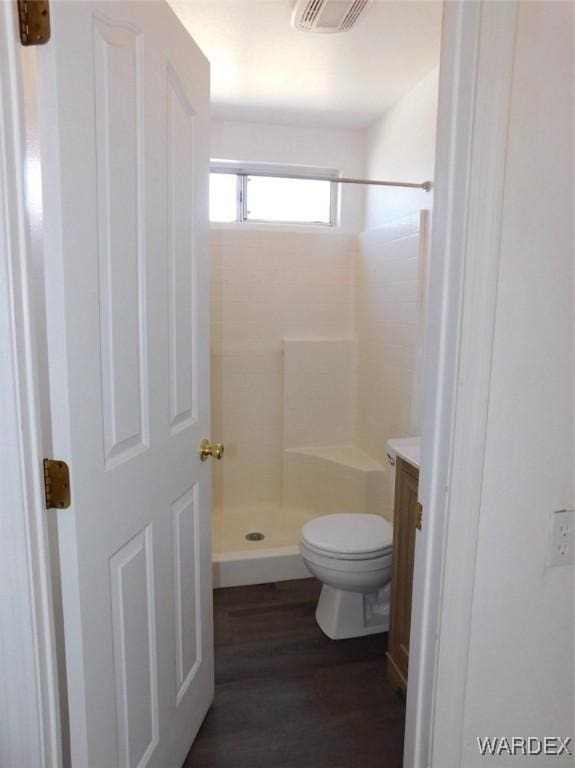 bathroom featuring visible vents, toilet, a shower stall, vanity, and wood finished floors