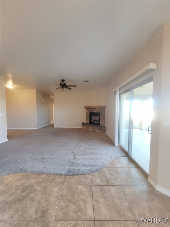 unfurnished living room with a ceiling fan, a glass covered fireplace, visible vents, and baseboards