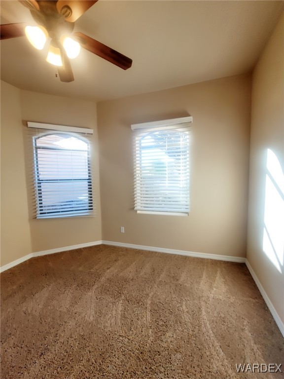 spare room featuring a ceiling fan and baseboards