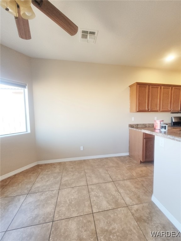 kitchen with ceiling fan, visible vents, baseboards, light countertops, and brown cabinets